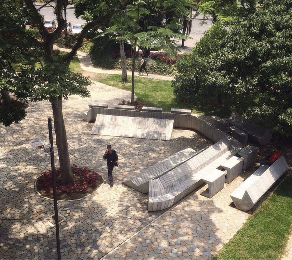 Espacio público ajardinado con vegetación, sombra y zonas de estancia en Medellín, Colombia.